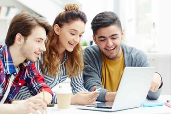 jovenes de un programa de practicas profesionales observan una laptop de trabajo